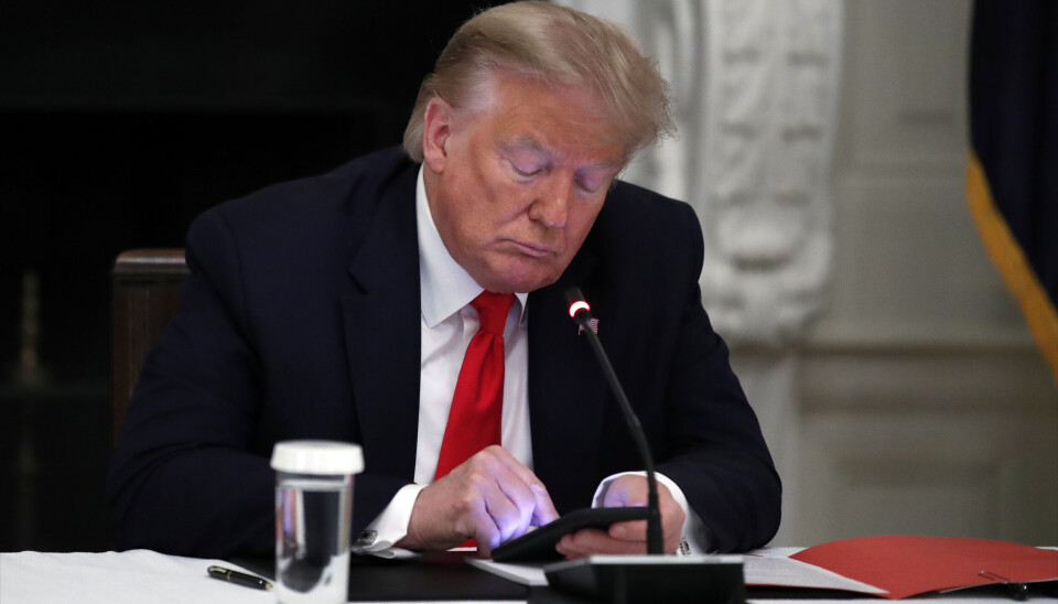 PÅVIRKET: Spørsmålet er ikke om norsk IT-bransje blir påvirket under en internasjonal handelskrig initiert av USA-president Donald Trump. Spørsmålet er hvor mye og hvordan. Man kan også bruke telefonen til å følge med slik Trump her gjorde under en rundebordskonferanse i 2020. (Foto: AP Photo)