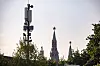 Cellular tower with modern antennas standing against historical Kremlin spires topped with red stars