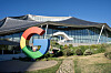 Stor Google-logo foran Bay View-campus med glassfasade og bølgende tak i Mountain View.