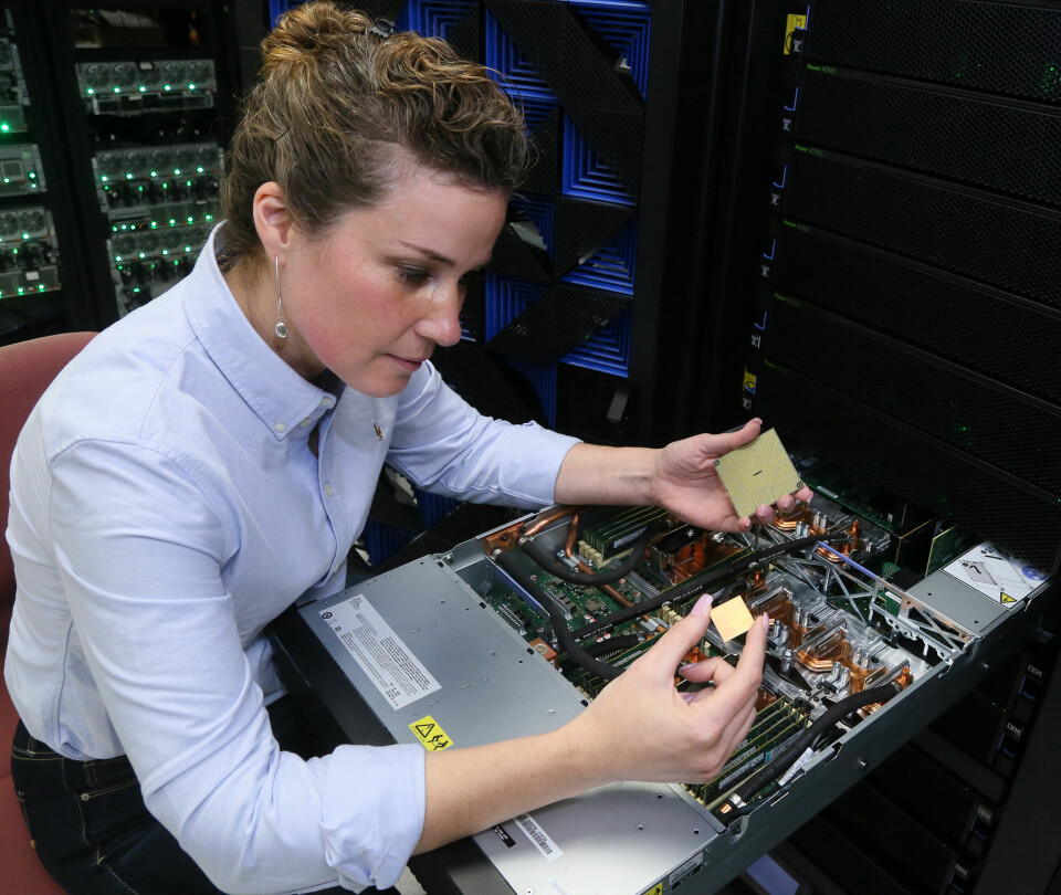 VISER: Testingeniør Stefanie Chiras i BM tester maskiner med Power9 i Austin Texas. I høyre hånd holder hun elektronikkbrikken med 8 millioner transistorer. I venstre hånd holder hun brikken ferdig innkapslet som plasseres i kontakten (socket). I den 2 U høye datamaskinen benyttes væske for å avlede varme slik at klokkefrekvensen kan være på 4 GHz. Foto IBM, Jack Plunket.